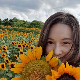 A woman with sunflowers partially covering her face